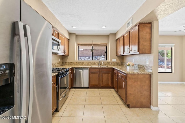 kitchen with a sink, stainless steel appliances, a textured ceiling, and visible vents