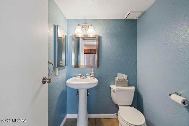 bathroom with toilet, a sink, visible vents, tile patterned flooring, and baseboards