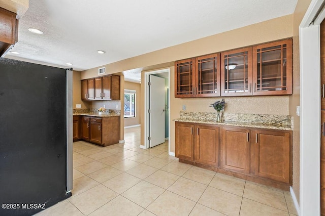 kitchen with freestanding refrigerator, visible vents, recessed lighting, light tile patterned floors, and light stone countertops