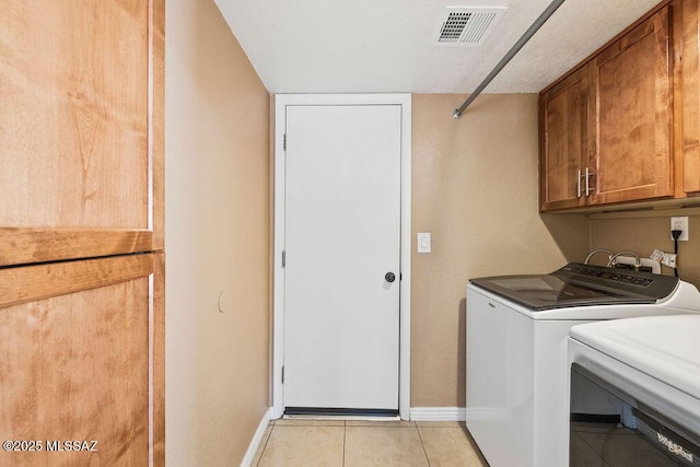 washroom with washing machine and dryer, light tile patterned floors, cabinet space, visible vents, and baseboards