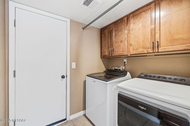 washroom with cabinet space, visible vents, separate washer and dryer, light tile patterned floors, and baseboards