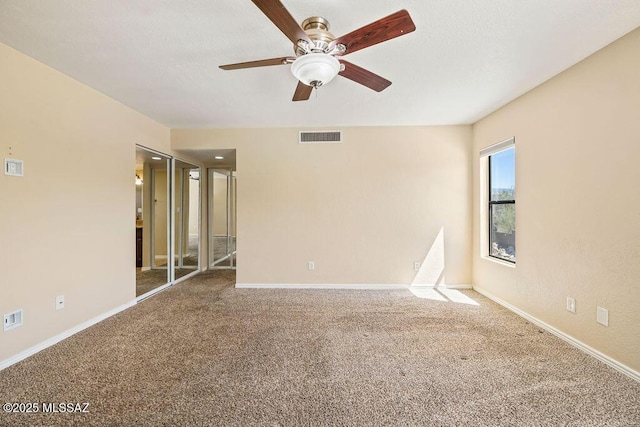 empty room featuring a ceiling fan, baseboards, visible vents, and carpet floors