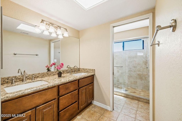 bathroom with double vanity, tile patterned floors, a tile shower, and a sink