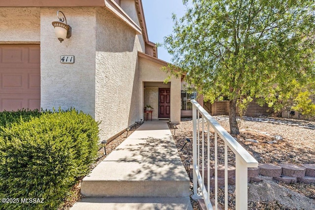 view of exterior entry featuring stucco siding and fence