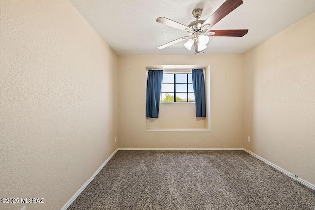 carpeted spare room featuring ceiling fan and baseboards