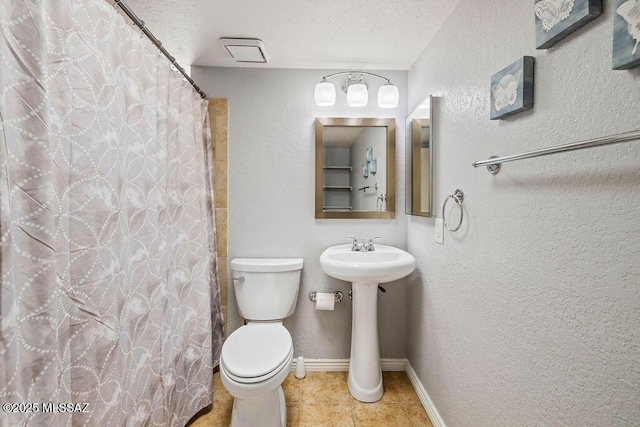 bathroom featuring toilet, a shower with curtain, tile patterned floors, baseboards, and a textured wall