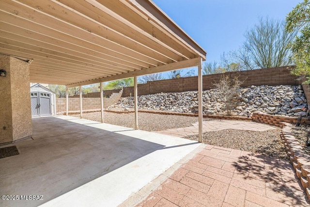 view of patio with an outdoor structure, a fenced backyard, and a shed