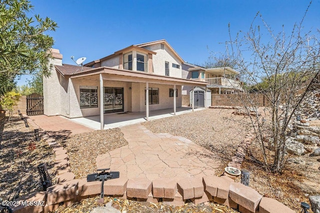 rear view of house featuring a gate, stucco siding, fence, a shed, and a patio area
