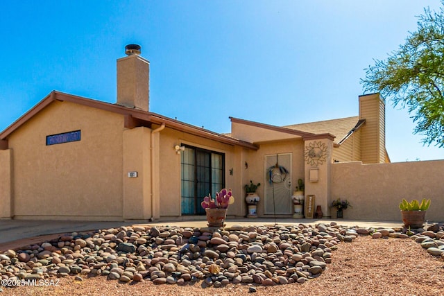 rear view of house with a patio, fence, a chimney, and stucco siding