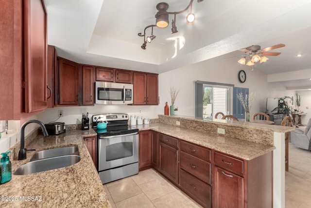 kitchen featuring a sink, appliances with stainless steel finishes, light tile patterned floors, and a peninsula