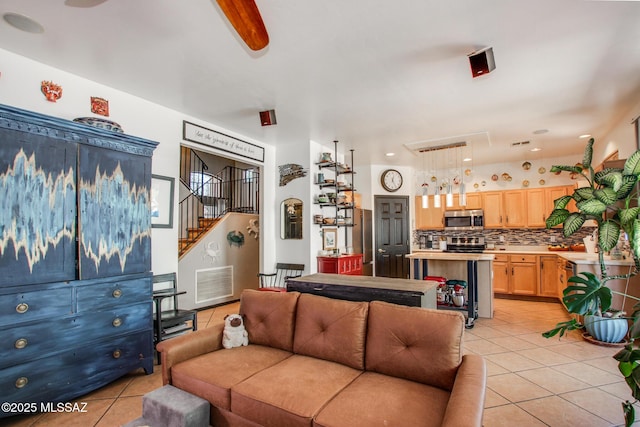 living room featuring stairs, visible vents, light tile patterned floors, and attic access