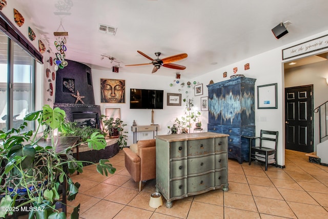 living room featuring light tile patterned floors, a ceiling fan, stairs, and visible vents