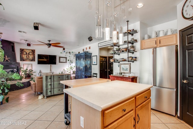 kitchen with freestanding refrigerator, light tile patterned flooring, a center island, and light countertops
