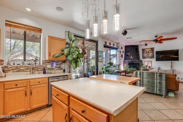 kitchen with dishwasher, a sink, light countertops, open floor plan, and light tile patterned flooring