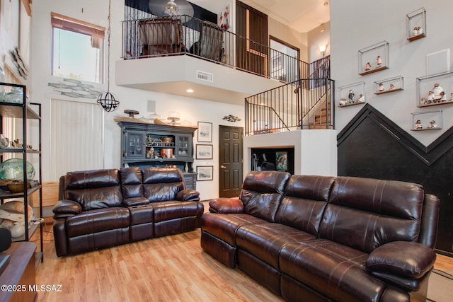 living room featuring visible vents, wood finished floors, and a towering ceiling