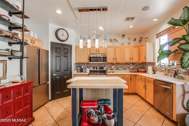 kitchen featuring stainless steel appliances, light tile patterned floors, a sink, and light brown cabinets
