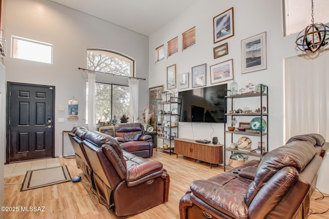 living area featuring a chandelier, light wood finished floors, and a towering ceiling