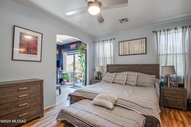 bedroom featuring visible vents, arched walkways, wood finished floors, and access to exterior