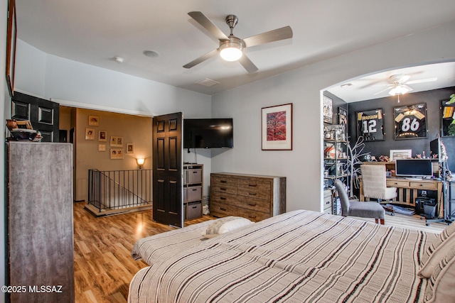 bedroom featuring arched walkways, ceiling fan, and wood finished floors