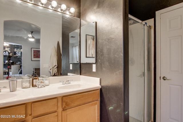 bathroom with a sink, a shower stall, a ceiling fan, and double vanity