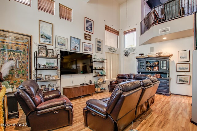 living room with visible vents, wood finished floors, and a towering ceiling