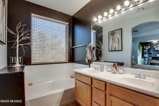 full bath featuring connected bathroom, visible vents, a sink, and a bath