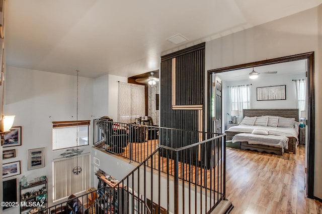 hall with wood finished floors and an upstairs landing