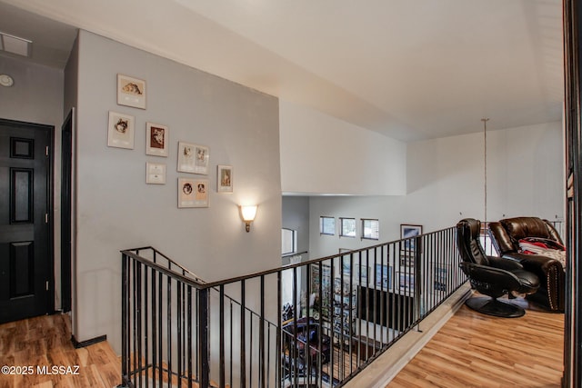 hallway with wood finished floors and an upstairs landing
