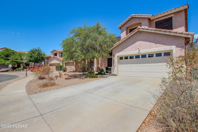 mediterranean / spanish home with a tiled roof, an attached garage, stucco siding, and driveway