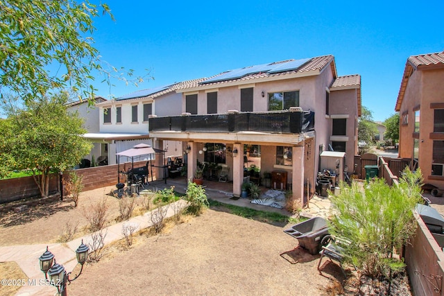 rear view of house featuring a fenced backyard, a gazebo, solar panels, and a patio area