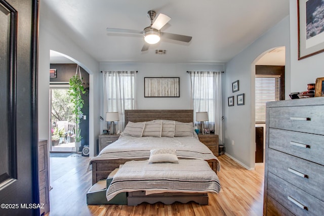 bedroom with a ceiling fan, visible vents, arched walkways, access to outside, and light wood-style flooring