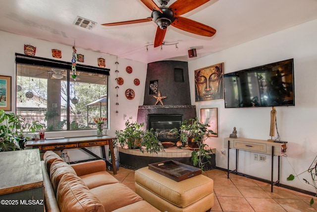 tiled living room with a ceiling fan, baseboards, visible vents, and a large fireplace