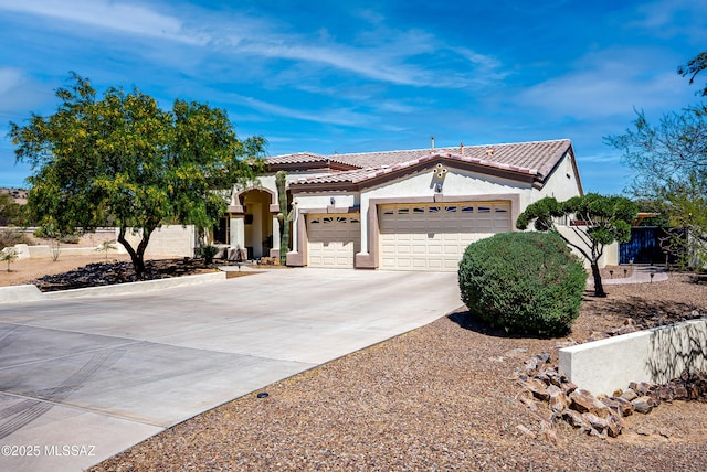 mediterranean / spanish home with a garage, stucco siding, a tile roof, and concrete driveway