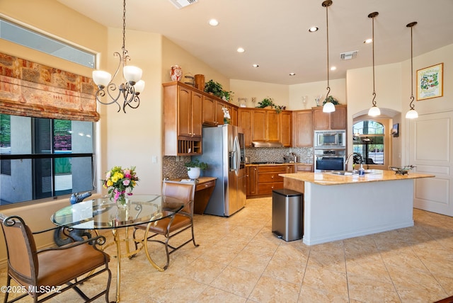 kitchen featuring visible vents, tasteful backsplash, a sink, hanging light fixtures, and stainless steel appliances