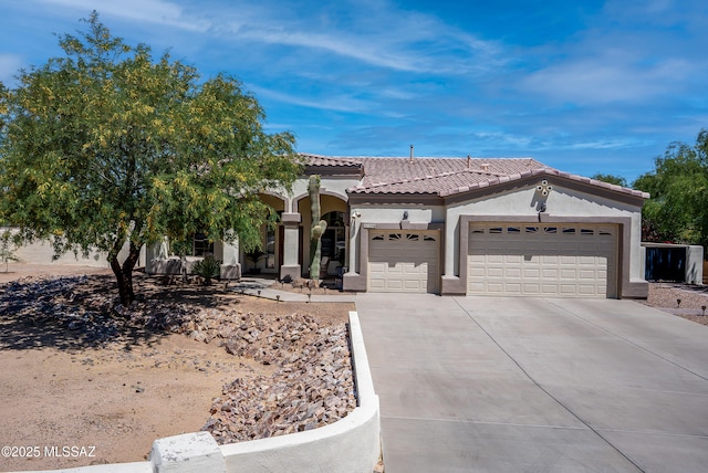mediterranean / spanish-style home with an attached garage, stucco siding, a tile roof, and concrete driveway