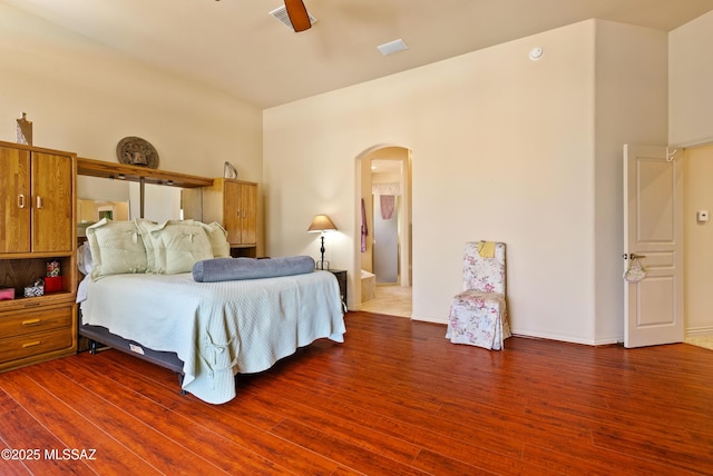 bedroom featuring arched walkways and wood finished floors