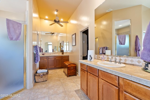 full bathroom with visible vents, a ceiling fan, two vanities, a shower stall, and a sink