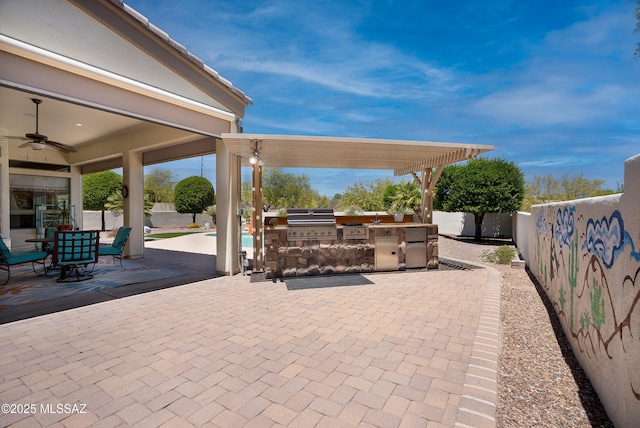 view of patio featuring exterior kitchen, area for grilling, a fenced backyard, outdoor dining area, and a ceiling fan