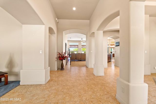 hallway featuring arched walkways and light tile patterned flooring