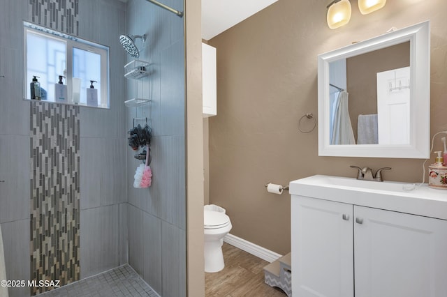 215 E Lester St, Tucson, AZ 85705 - full bathroom featuring a tile shower, wood finished floors, vanity, baseboards, and toilet
