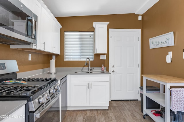 215 E Lester St, Tucson, AZ 85705 - kitchen with a sink, light countertops, stainless steel appliances, white cabinetry, and light wood-type flooring