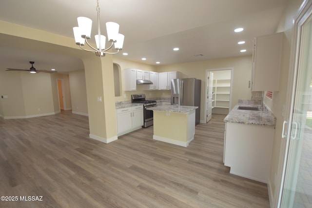 kitchen with appliances with stainless steel finishes, arched walkways, open floor plan, under cabinet range hood, and recessed lighting