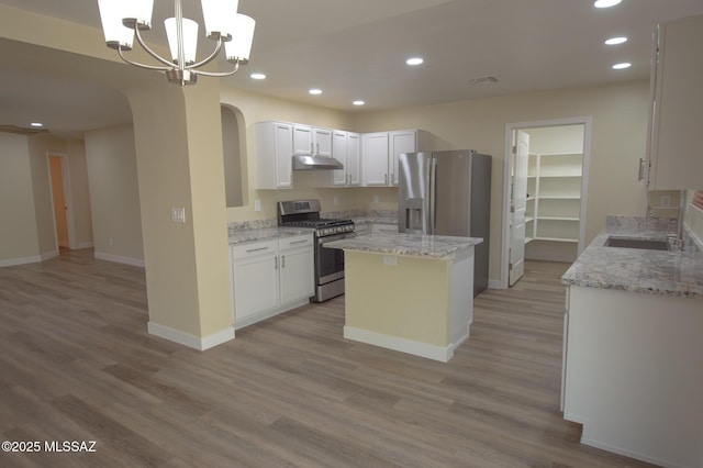 kitchen featuring recessed lighting, arched walkways, under cabinet range hood, and stainless steel appliances