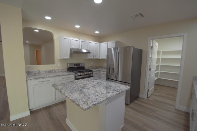 8769 E Green Branch Ln, Tucson, AZ 85730 - kitchen featuring visible vents, light wood finished floors, under cabinet range hood, and stainless steel appliances