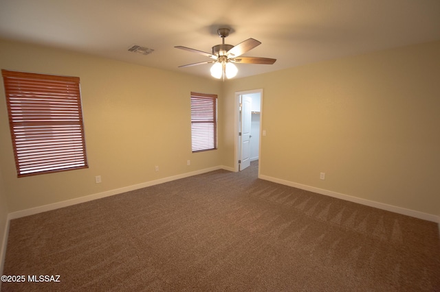 empty room with baseboards, a ceiling fan, dark colored carpet, and visible vents