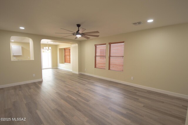 8769 E Green Branch Ln, Tucson, AZ 85730 - empty room with visible vents, dark wood-style flooring, baseboards, recessed lighting, and ceiling fan with notable chandelier