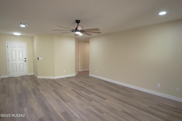 empty room featuring a ceiling fan, baseboards, recessed lighting, wood finished floors, and visible vents