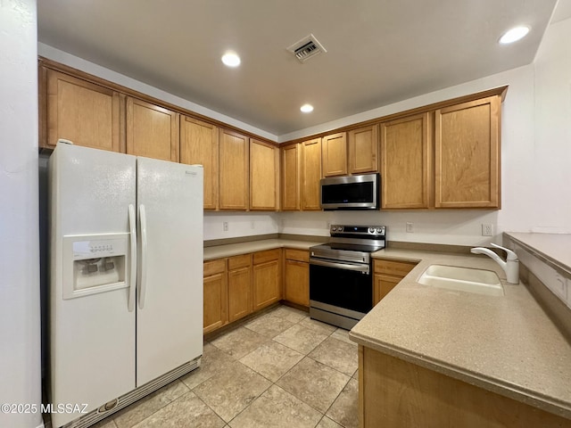 kitchen with brown cabinetry, visible vents, appliances with stainless steel finishes, a sink, and recessed lighting