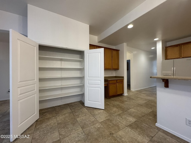 kitchen featuring open shelves, brown cabinets, fridge with ice dispenser, baseboards, and recessed lighting