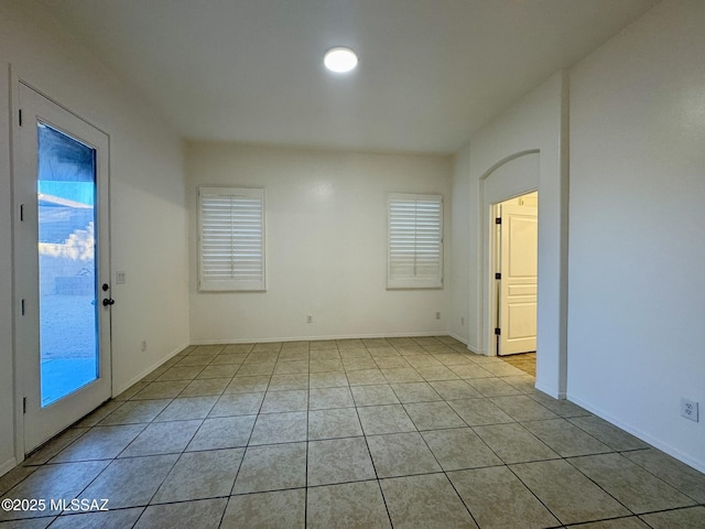 empty room featuring baseboards and light tile patterned flooring